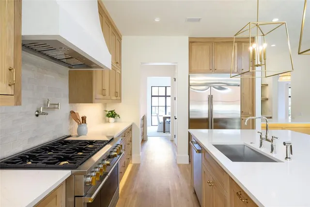 a kitchen with stainless steel appliances a sink a stove and wooden floor