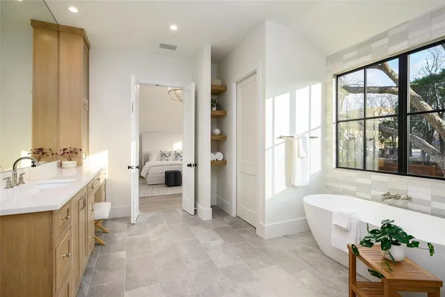 a spacious bathroom with a double vanity sink a large mirror and a bathtub
