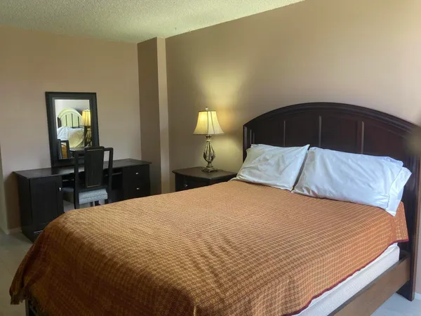 a bedroom with a bed and a lamp on dresser