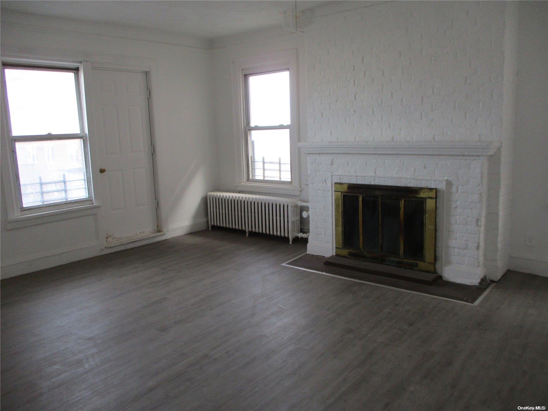 135 Beach 124th Street Queens, NY 11694 - Photo 11 of 25 an empty room with wooden floor fireplace and windows