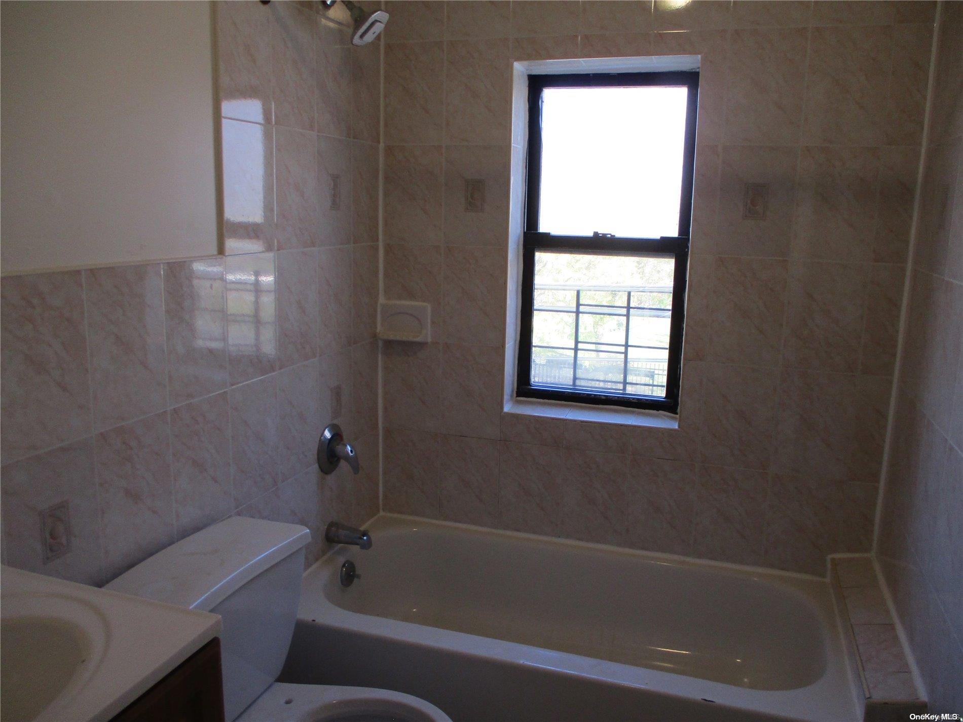 135 Beach 124th Street Queens, NY 11694 - Photo 4 of 25 a bathroom with a bathtub toilet and window