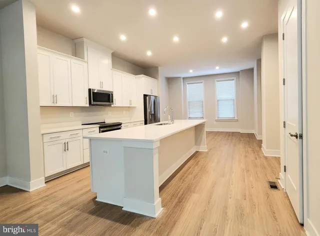 a large white kitchen with kitchen island a sink a stove and white cabinets