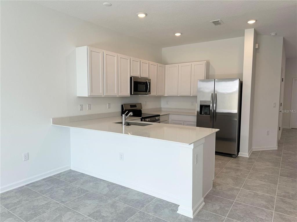2452 Skyline Loop Kissimmee, FL 34758 - Photo 2 of 12 a kitchen with kitchen island white cabinets and refrigerator