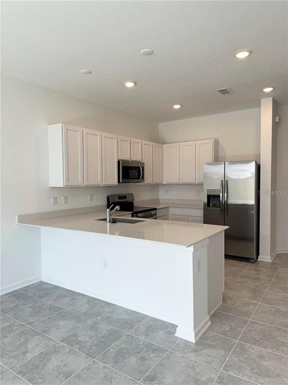 2452 Skyline Loop Kissimmee, FL 34758 - Photo 7 of 12 a kitchen with stainless steel appliances a refrigerator sink and microwave