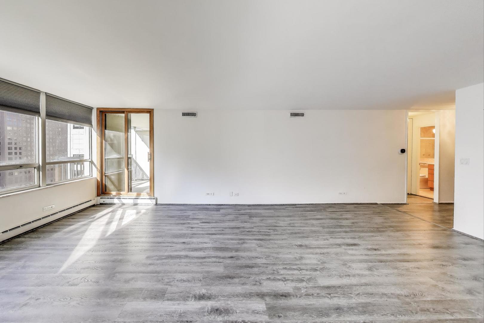 201 East Chestnut Street, Unit 19F Chicago, IL 60611 - Photo 9 of 36 a view of an empty room with a window and wooden floor