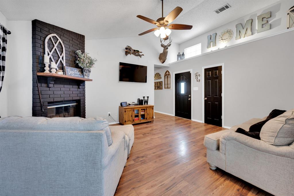 1003 Short Line Boulevard Midlothian, TX 76065 - Photo 13 of 25 Living area with a brick fireplace, wood finished floors, ceiling fan, and vaulted ceiling