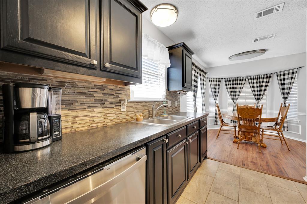 1003 Short Line Boulevard Midlothian, TX 76065 - Photo 16 of 25 Kitchen with dishwasher, dark countertops, decorative backsplash, a textured ceiling, and light tile patterned floors