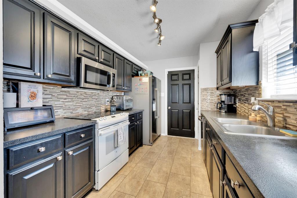 1003 Short Line Boulevard Midlothian, TX 76065 - Photo 17 of 25 Kitchen with stainless steel appliances, dark countertops, and light tile patterned floors