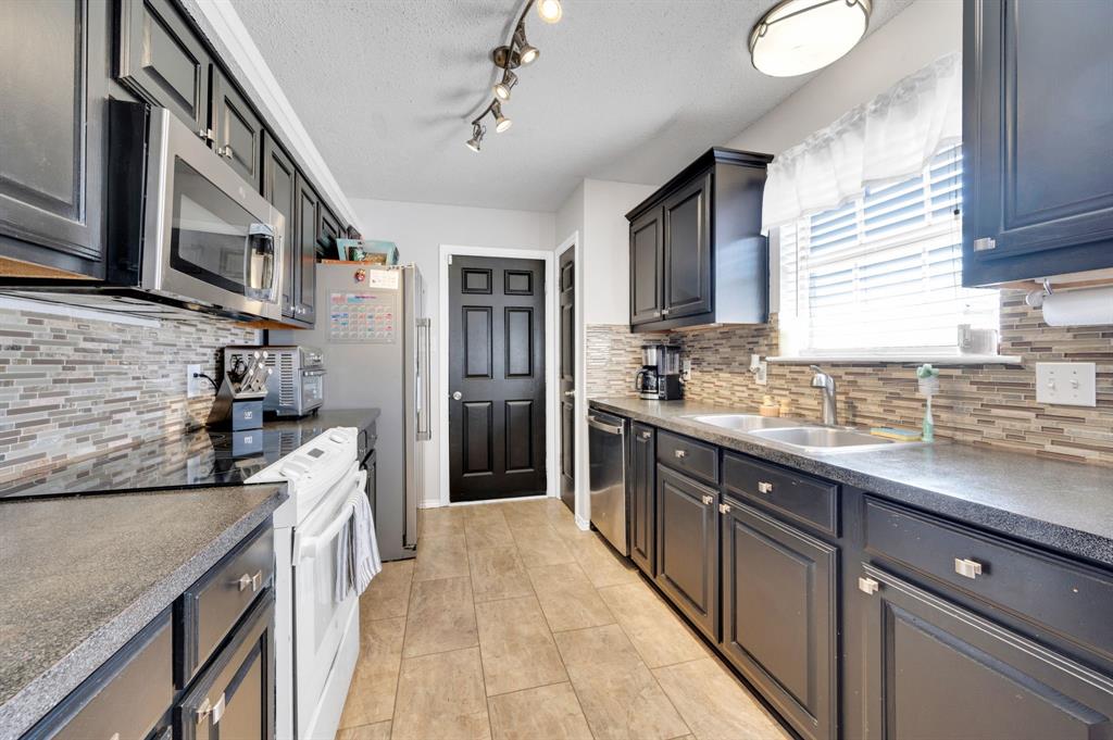 1003 Short Line Boulevard Midlothian, TX 76065 - Photo 18 of 25 Kitchen featuring stainless steel appliances, a textured ceiling, and backsplash