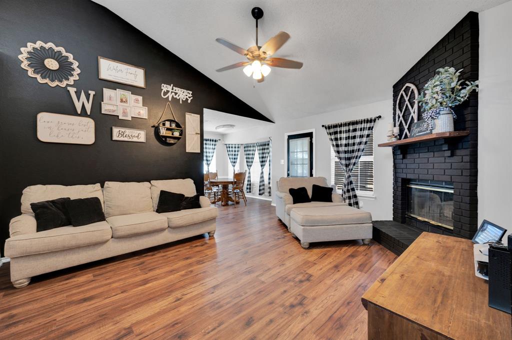 1003 Short Line Boulevard Midlothian, TX 76065 - Photo 2 of 25 Living room featuring wood finished floors, lofted ceiling, a brick fireplace, and ceiling fan