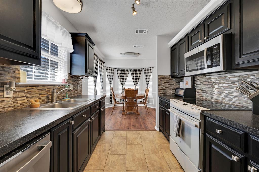 1003 Short Line Boulevard Midlothian, TX 76065 - Photo 4 of 25 Kitchen featuring stainless steel appliances, dark countertops, dark cabinetry, decorative backsplash, and a textured ceiling