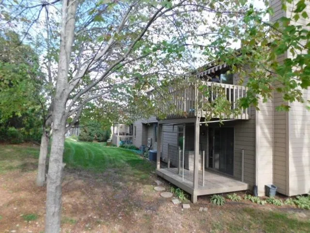 a view of a small house with large tree and wooden fence