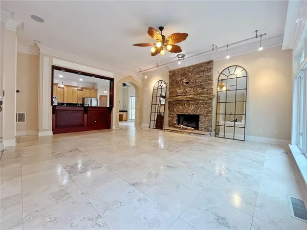 an empty room with wooden floor fireplace and windows