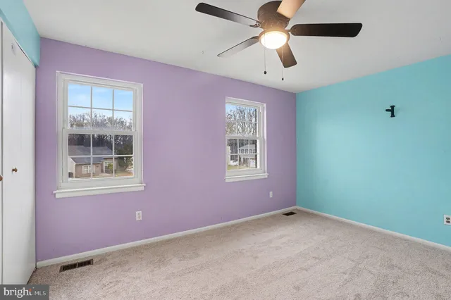 an empty room with windows and fan