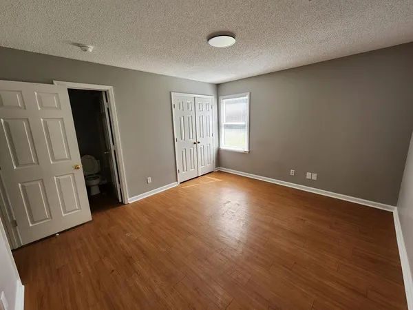 an empty room with wooden floor and closet