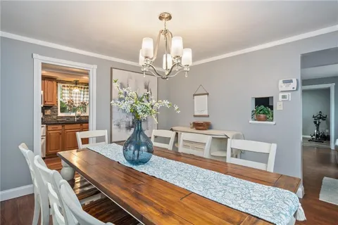 a dining room with wooden floor a chandelier a wooden table and chairs