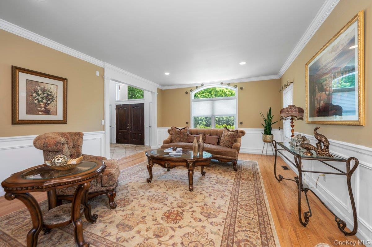 129 Round Swamp Road Huntington, NY 11743 - Photo 8 of 49 Spacious living area featuring hardwood flooring, crown molding, chair rail with wainscoting, a large arched window, and recessed lighting