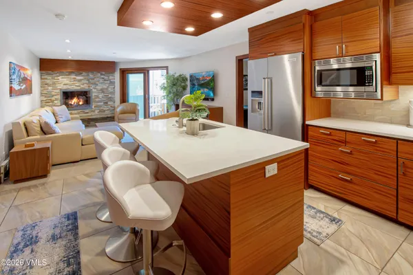 a large kitchen with stainless steel appliances kitchen island granite countertop a table chairs and a refrigerator