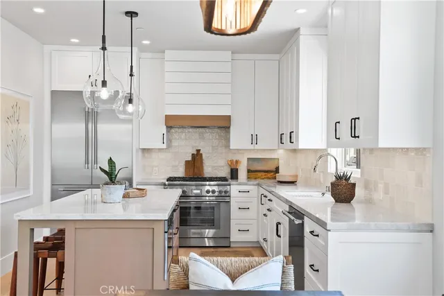 a kitchen with stainless steel appliances kitchen island granite countertop a sink a stove and a refrigerator