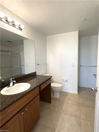 a bathroom with a granite countertop sink a toilet a mirror and bathtub