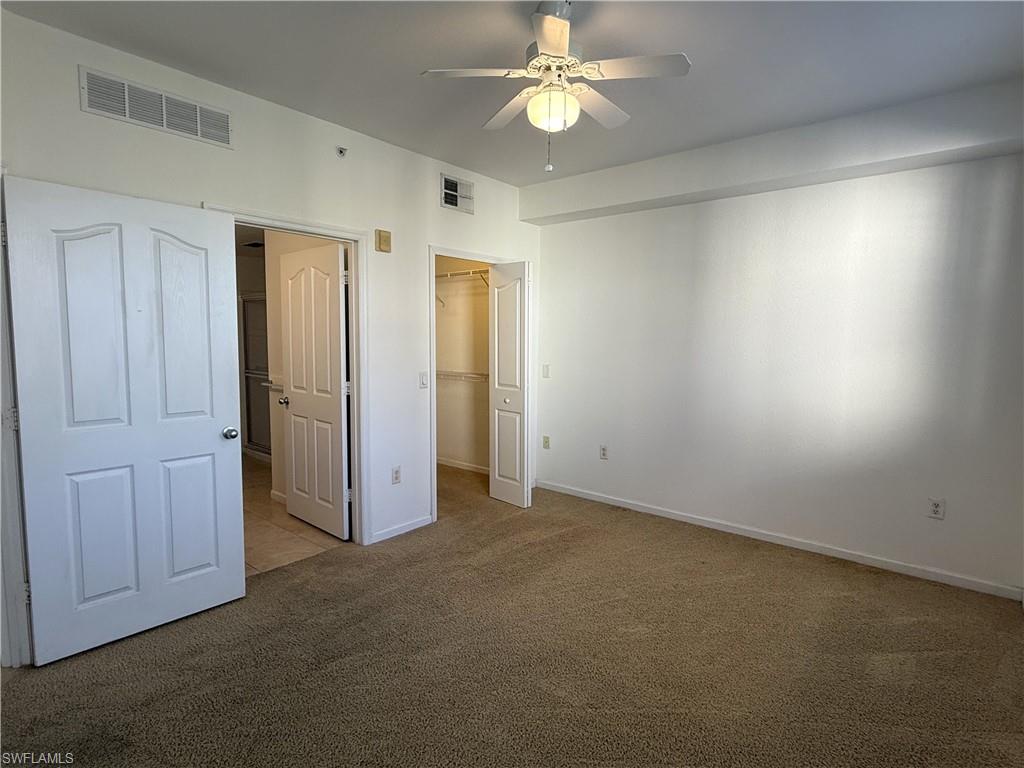 12990 Positano Circle, Unit 208 Naples, FL 34105 - Photo 7 of 20 an empty room with a chandelier fan and closet area