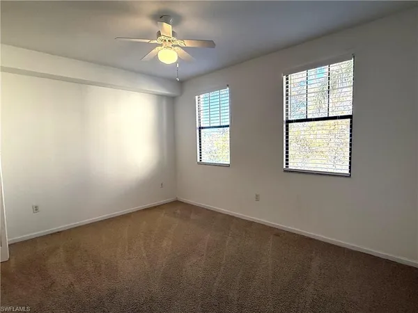 an empty room with a window and a fan