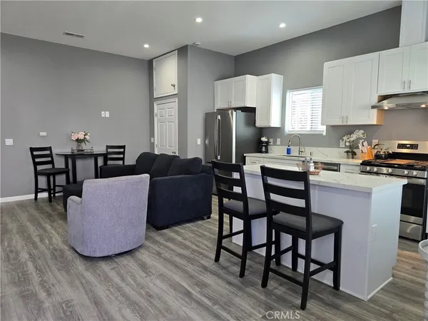 a living room with furniture a wooden floor and a kitchen view