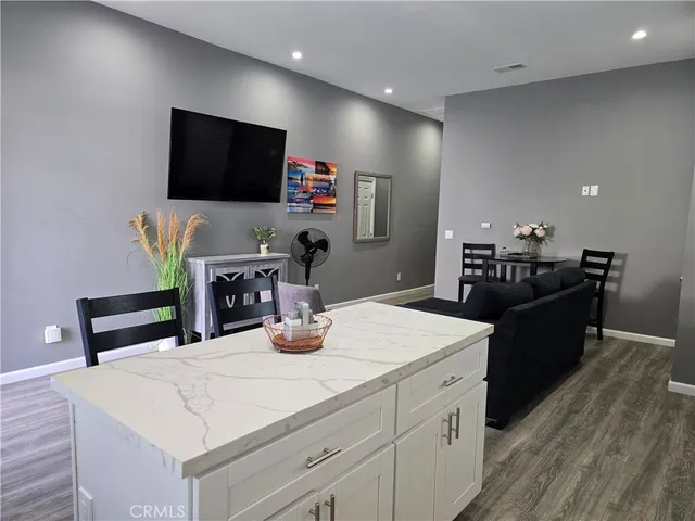 a living room with stainless steel appliances kitchen island granite countertop a table chairs microwave and sink