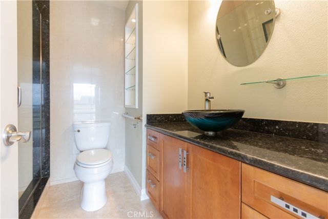 a bathroom with a granite countertop sink a toilet and a mirror