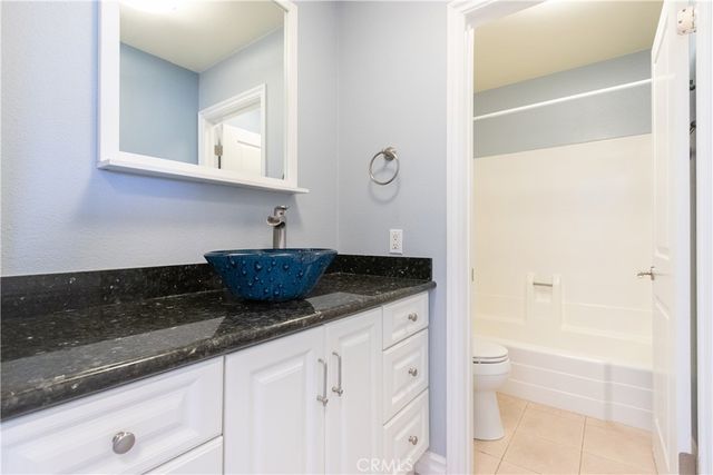 a bathroom with a granite countertop sink a toilet and bathtub