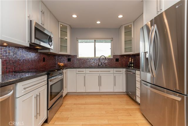 a kitchen with stainless steel appliances granite countertop a refrigerator sink and microwave