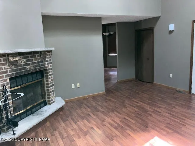 a view of empty room with wooden floor and fireplace