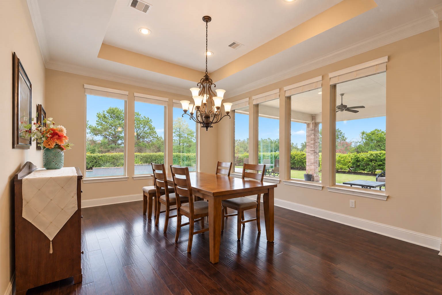 91 Lake View Loop Fulshear, TX 77441 - Photo 13 of 42 Check out this stunning dining room, encompassed in picture windows overlooking the backyard oasis. This space boasts hardwood floors, a graceful tray ceiling, and an elegant chandelier, creating a bright and dimensional setting for gatherings.