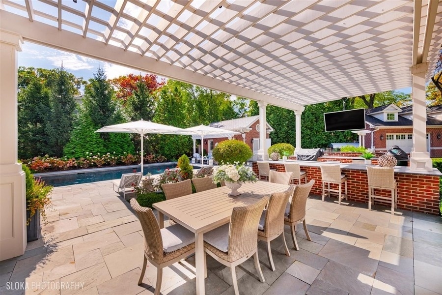 660 Prospect Avenue Winnetka, IL 60093 - Photo 17 of 77 a view of a patio with a dining table and chairs under an umbrella with a big yard