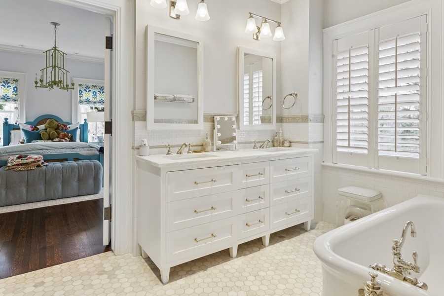 660 Prospect Avenue Winnetka, IL 60093 - Photo 53 of 77 a en suite bathroom with a double vanity sink a mirror a bathtub and next to a window