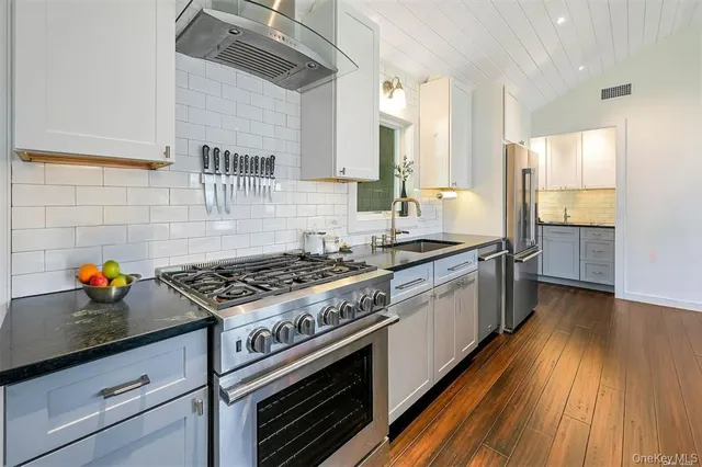 a kitchen with stainless steel appliances a stove a sink dishwasher and a refrigerator with wooden floor