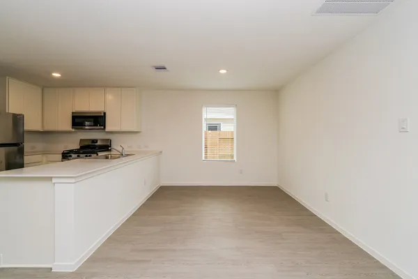 a kitchen with a refrigerator a stove top oven and white cabinets