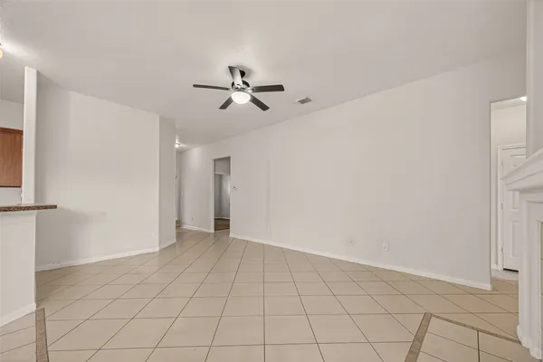 a view of an empty room with chandelier fan and fireplace