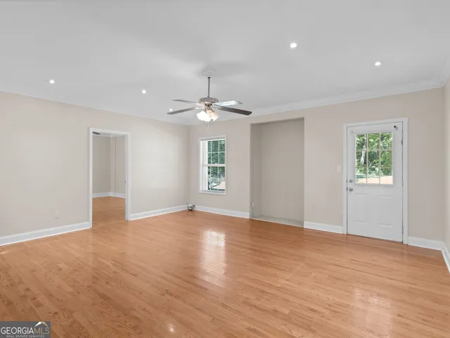 an empty room with wooden floor cabinet and windows