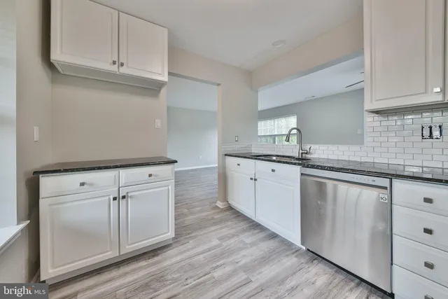 a kitchen with stainless steel appliances granite countertop a sink dishwasher a stove and a refrigerator with wooden floor