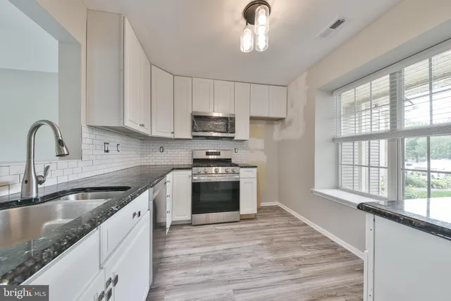 a kitchen with stainless steel appliances granite countertop a stove a sink and a microwave