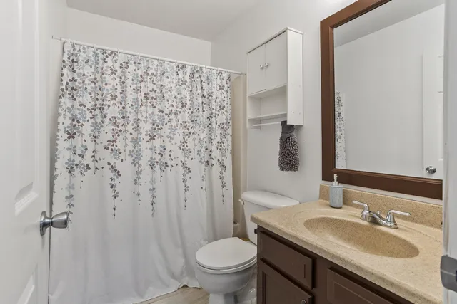 a bathroom with a granite countertop sink toilet and mirror