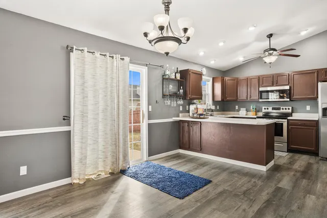 a kitchen with stainless steel appliances granite countertop a refrigerator a sink dishwasher a stove and white countertops with wooden floor