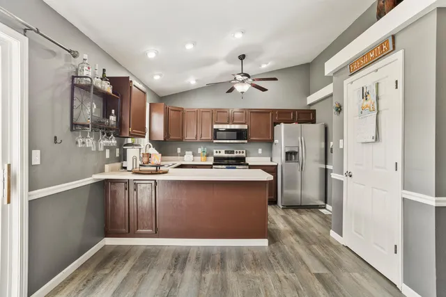 a kitchen with stainless steel appliances granite countertop a refrigerator a sink dishwasher and a stove with wooden floor