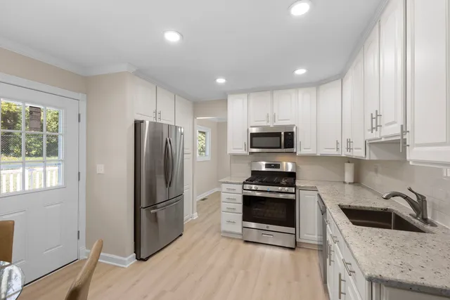 a kitchen with granite countertop a refrigerator a sink a stove a microwave and island