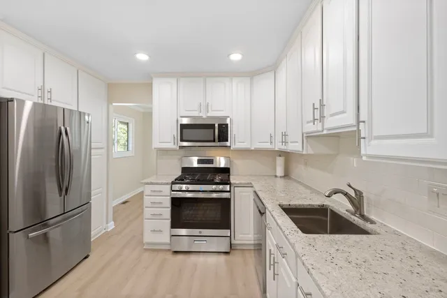 a kitchen with white cabinets sink and stainless steel appliances