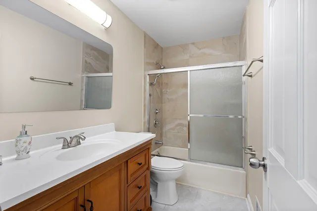a bathroom with a shower sink vanity mirror and toilet