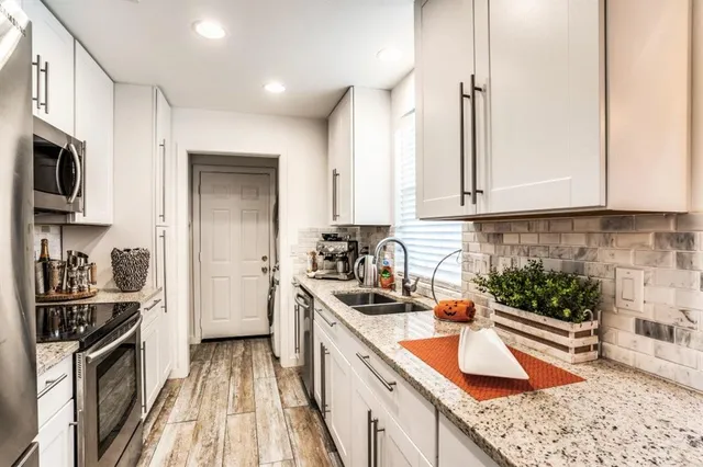 a kitchen with stainless steel appliances granite countertop a stove a sink and a refrigerator