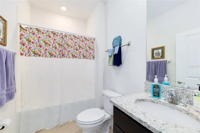 a bathroom with a granite countertop sink a toilet and shower