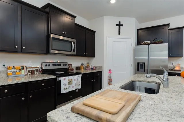 a kitchen with stainless steel appliances granite countertop a refrigerator a stove a microwave a sink and chairs